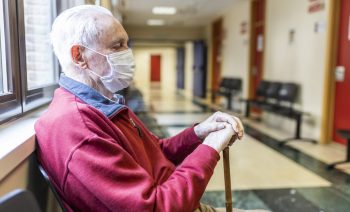 elderly man sitting in doctor's office in a hospital with respirator, side view